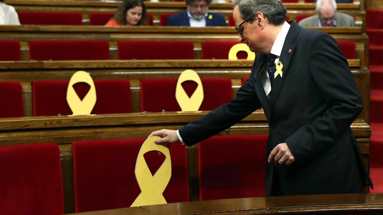 El presidente de la Generalitat, Quim Torra, coloca un lazo amarillo en un pleno del Parlamento catalán.