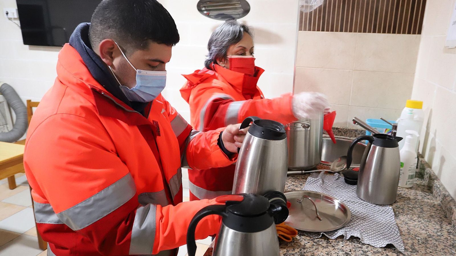 Voluntarios de Cruz Roja preparan comida caliente para el reparto durante la noche