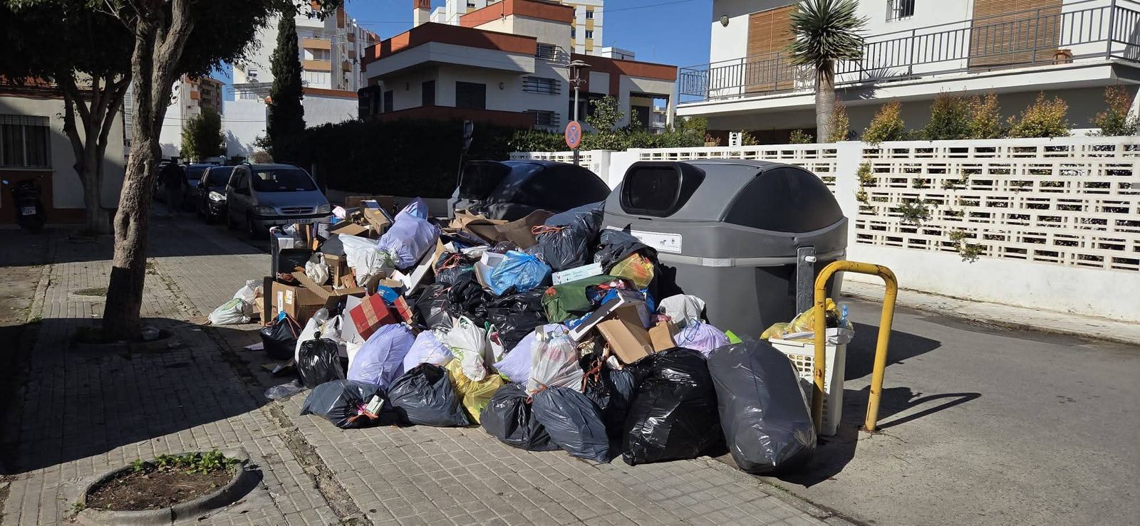 Bolsas de basura en la acera, delante de los nuevos contenedores.