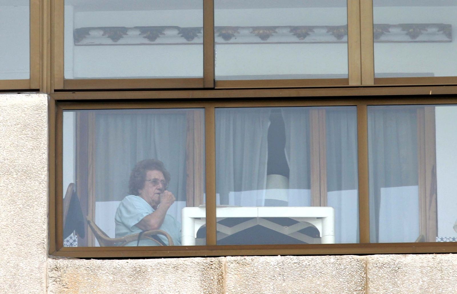 Una mujer que vive sola vista desde el exterior de una ventana del edificio en el que reside.