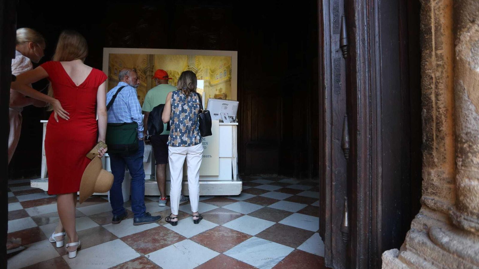 Varias personas esta tarde en la puerta del patio de los Naranjos de la Catedral de Málaga.