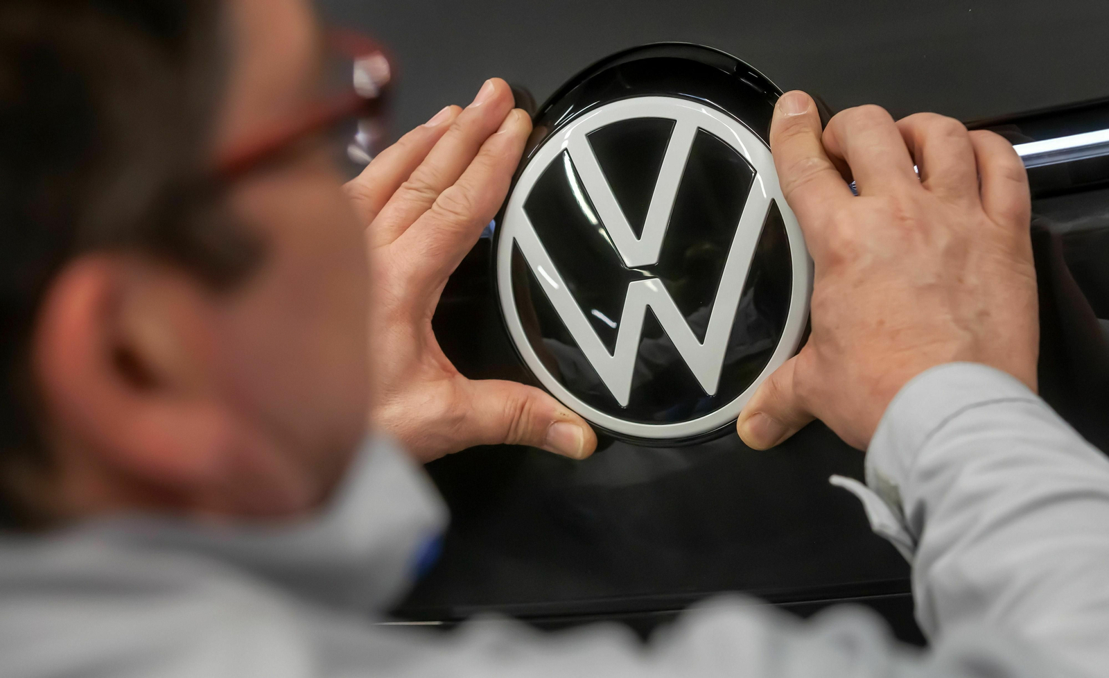 Un operario coloca el logotipo de Volkswagen en un coche
