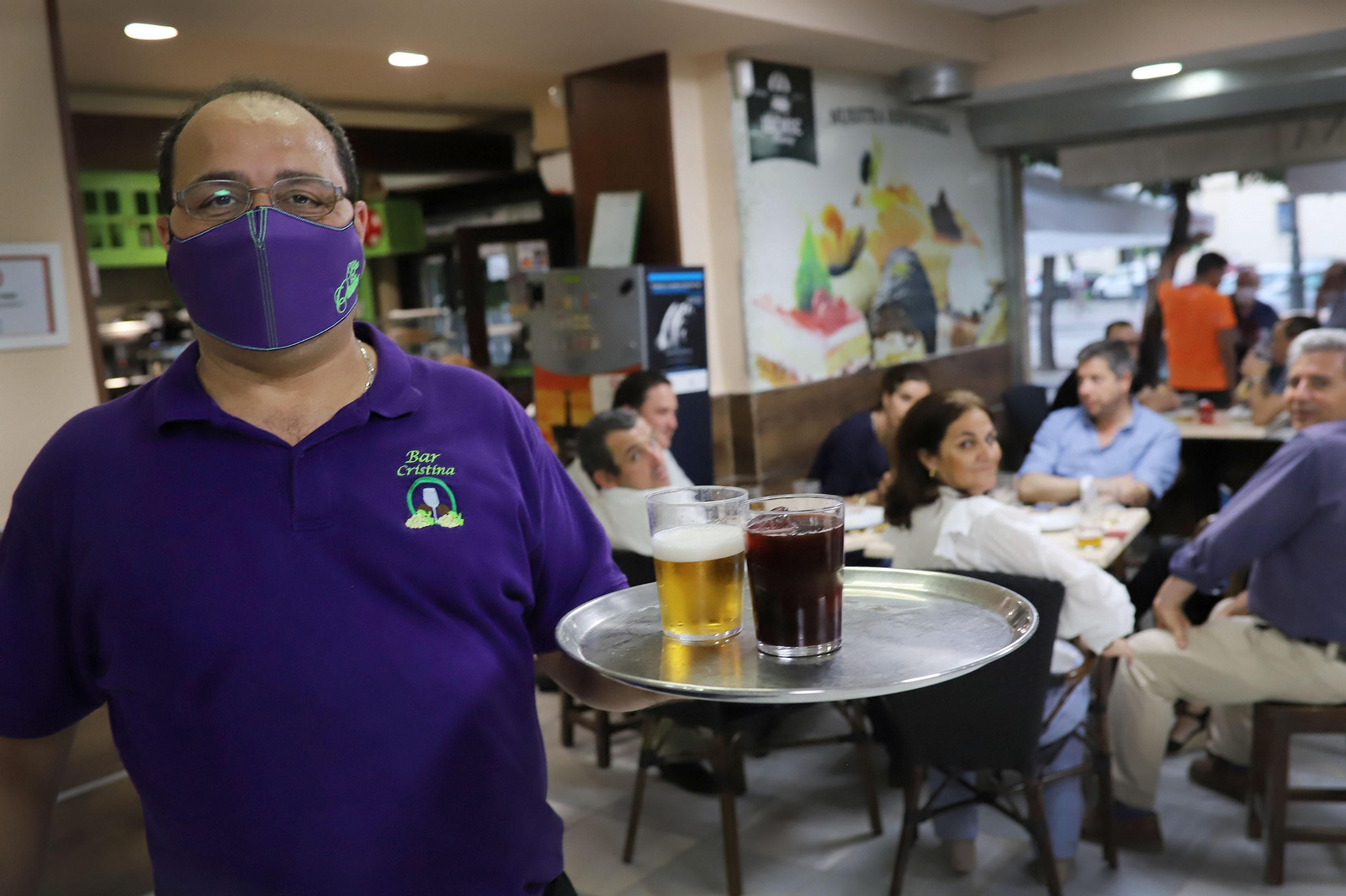 Un camarero del Bar Cristina se dispone a servir una mesa en el interior del establecimiento.