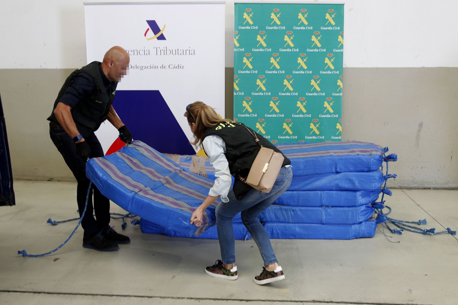 Dos agentes, con los fardos de la cocaína aprehendida.