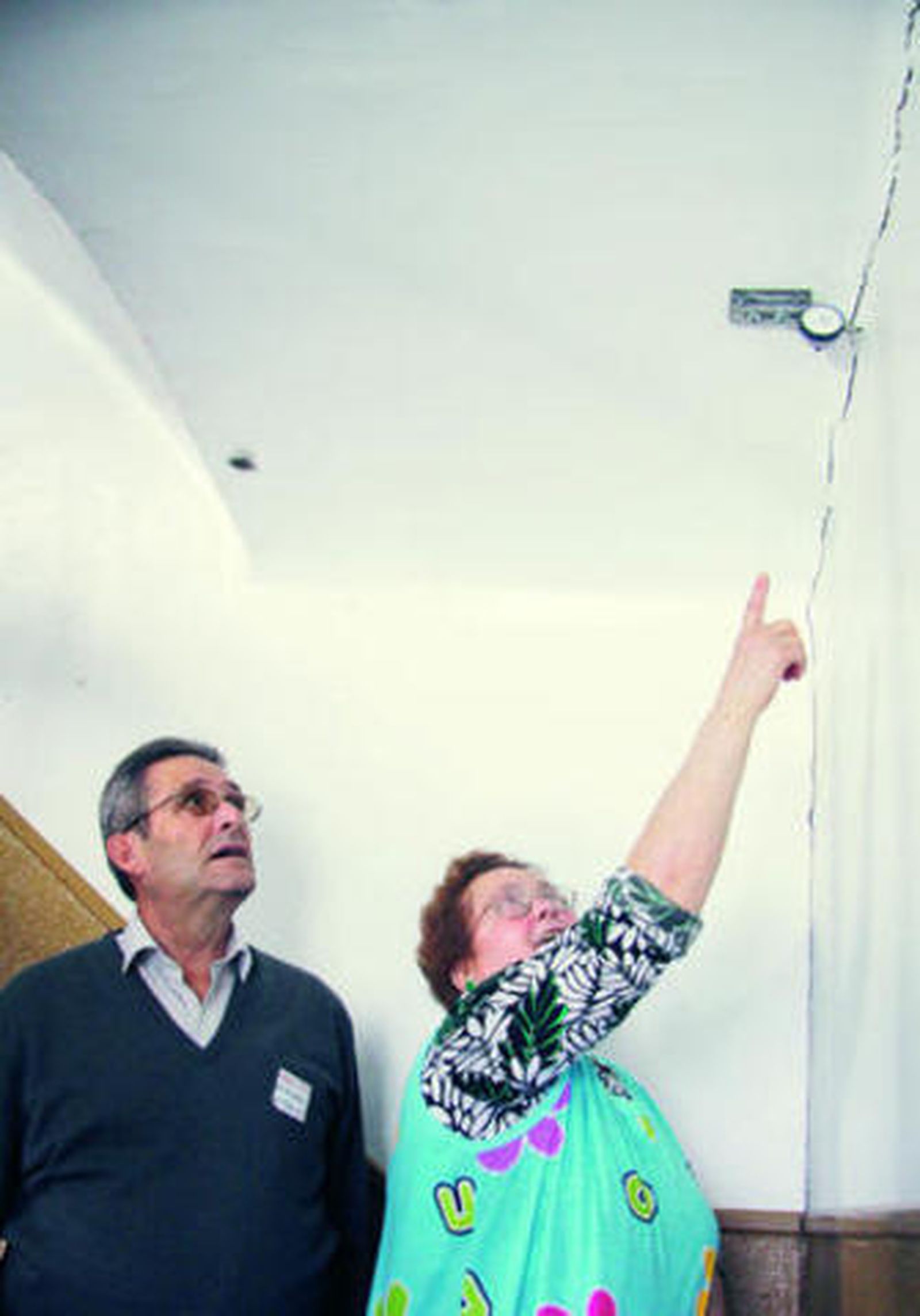 Dos vecinos observan las grietas aparecidas en una escalera.