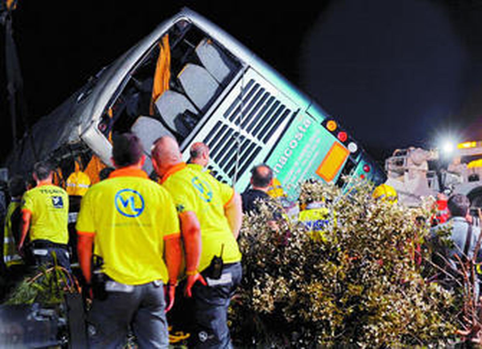 Bomberos y personal de emergencias observan el autobús siniestrado.
