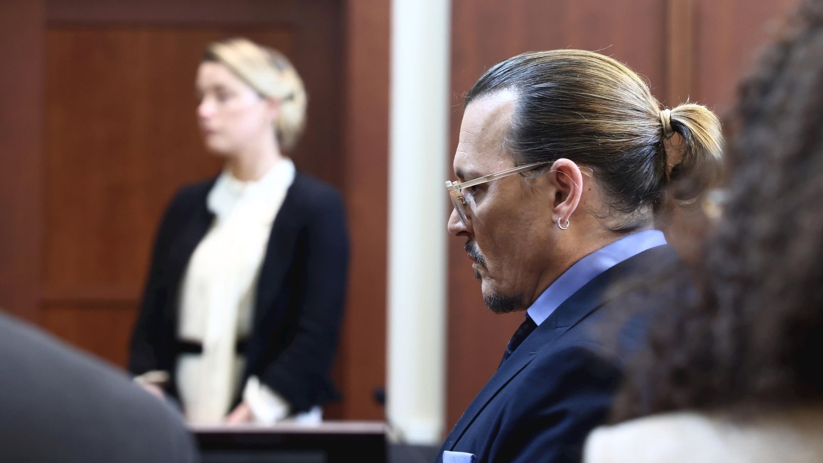 Johnny Depp en primer plano, mientras su ex mujer, Amber Heard, presta juramento antes de su testimonio.