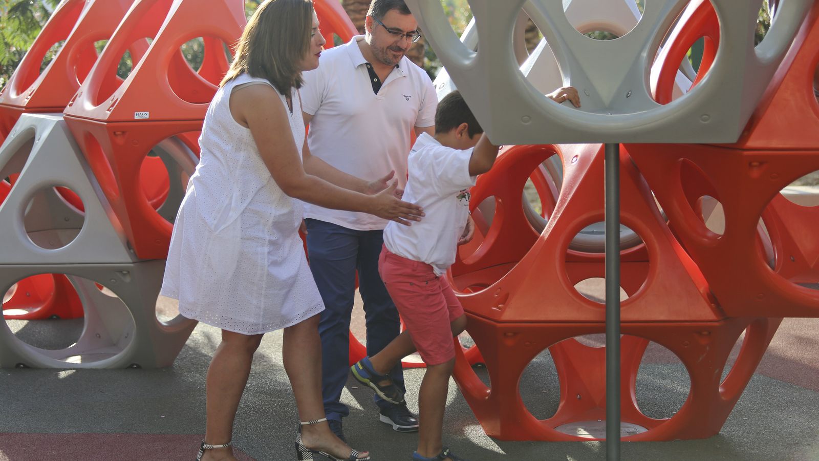 Los padres de Pablo lo ayudan a subirse a una estructura de un parque.