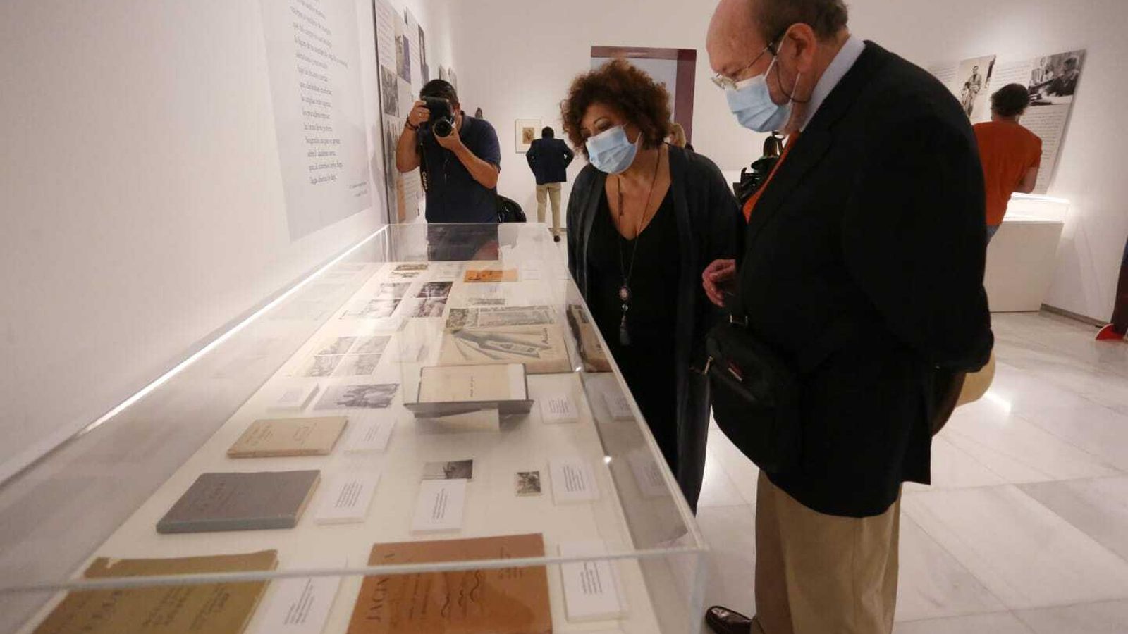 Asistentes a la inauguración de la exposición observan uno de los libros.