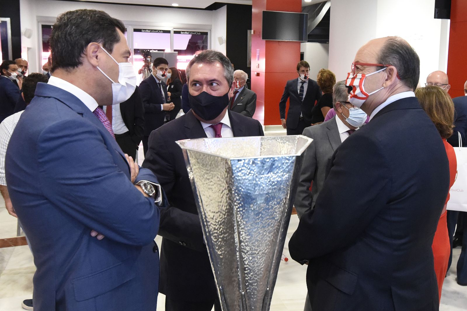 Juanma Moreno, Juan Espadas y José Castro dialogan delante del trofeo de la Europa League.
