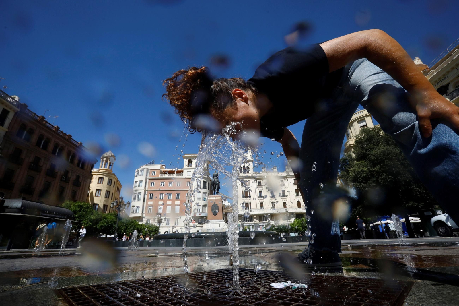 Una joven se refresca en una de las fuentes de la plaza de las Tendillas.