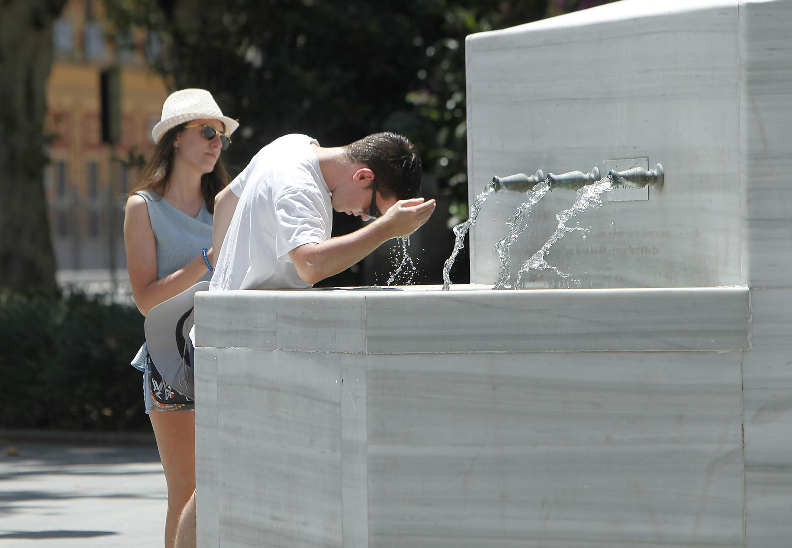Dos turistas se refrescan en una fuente de la ciudad.