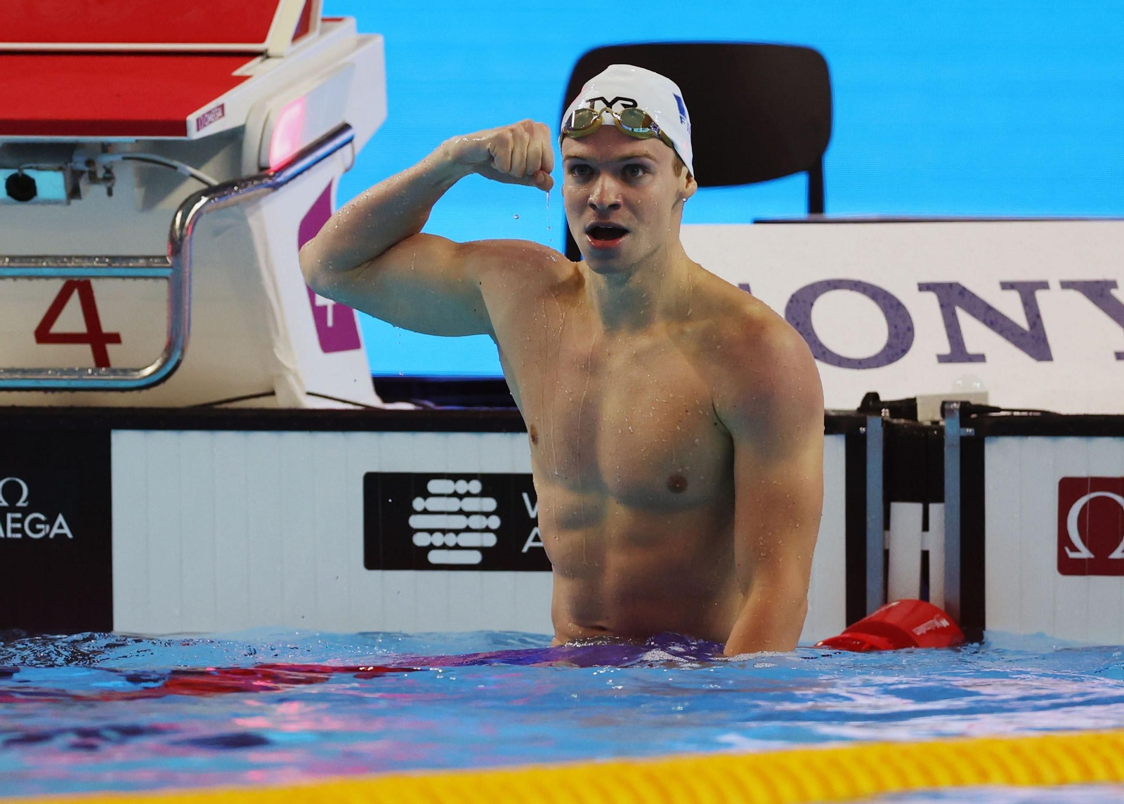 Leon Marchand festeja, marcando bíceps, su nuevo oro y récord mundial