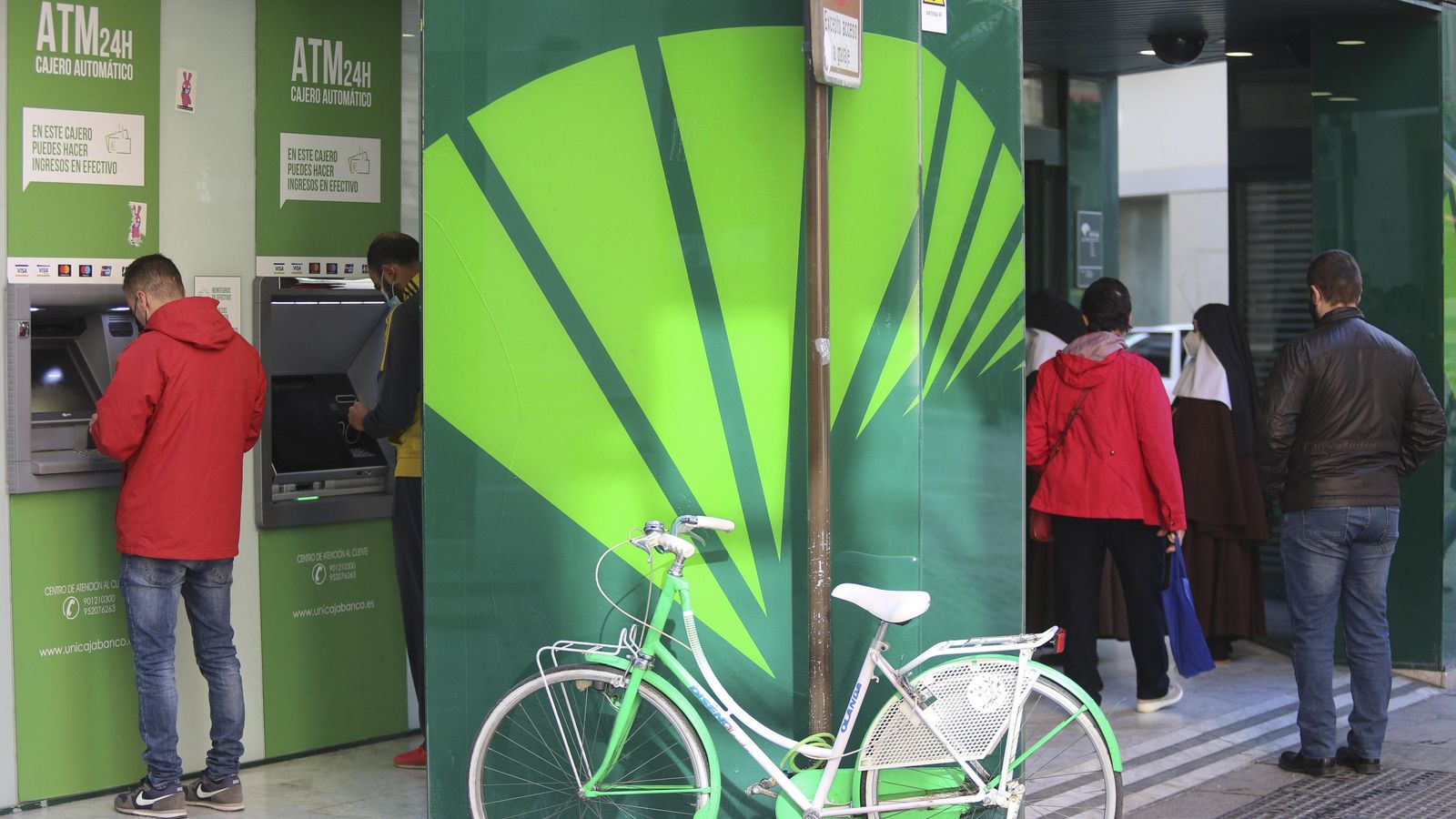 Varios clientes, este martes en una oficina de Unicaja Banco en Málaga capital.