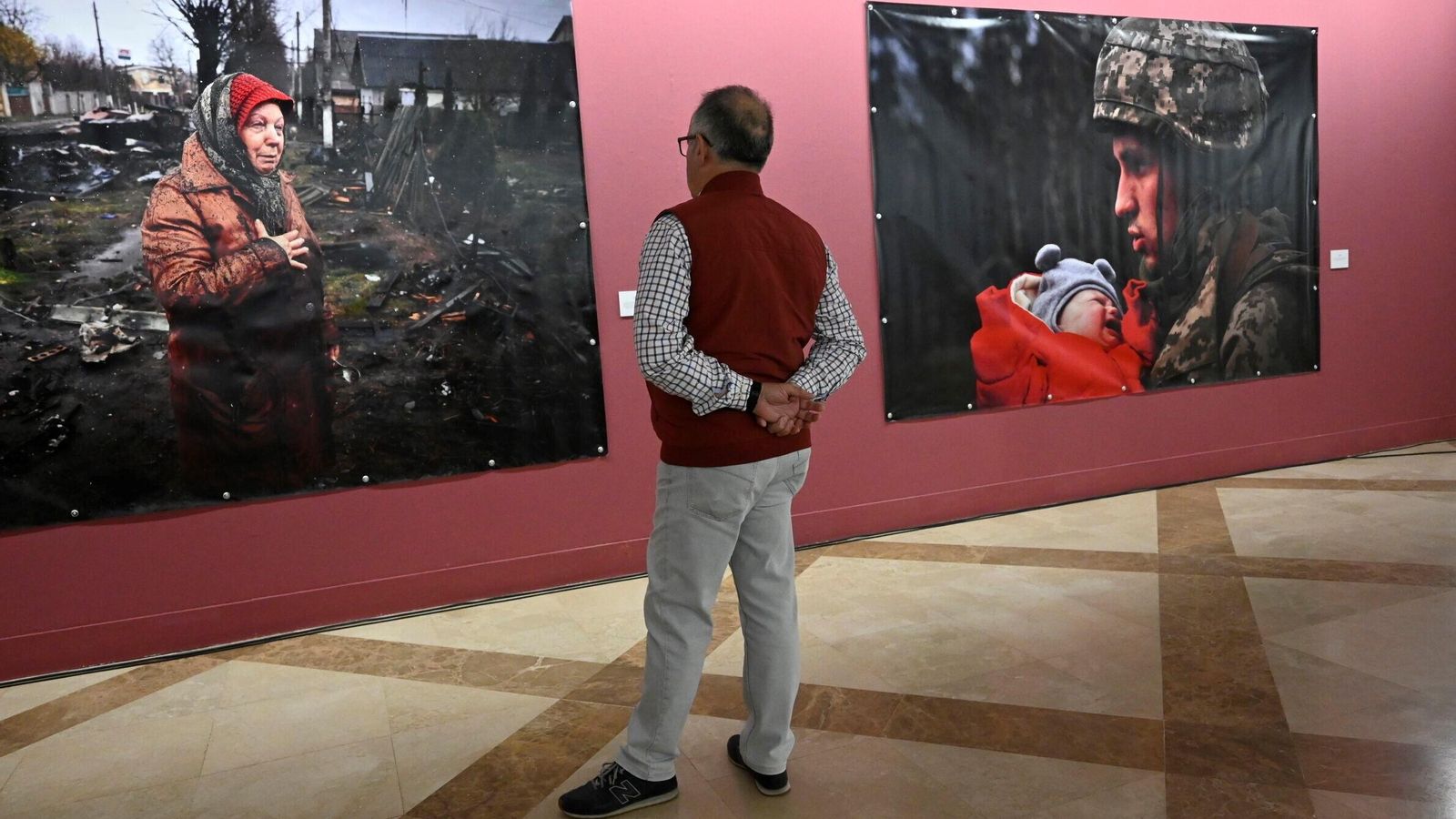 Hombre observa las fotografías de la Exposición "Ucrania, la guerra de los civiles". Hombre observa las fotografías de la Exposición "Ucrania, la guerra de los civiles".