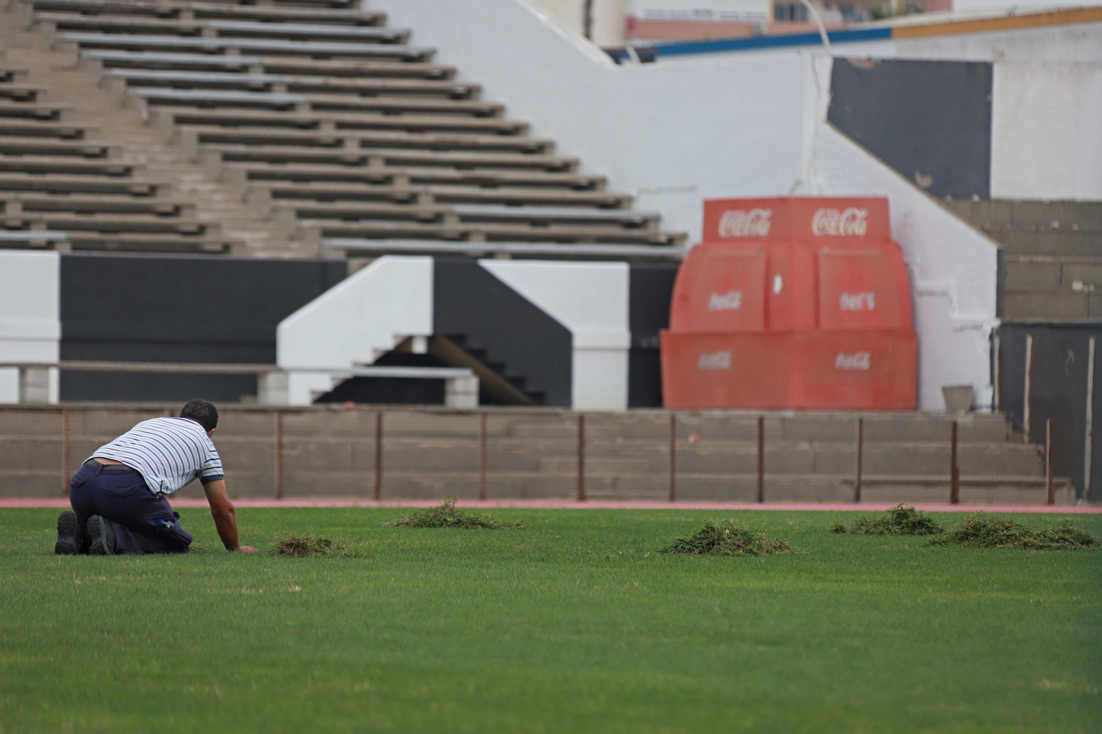 Un operario lleva a cabo trabajos en el césped del estadio Municipal de La Línea