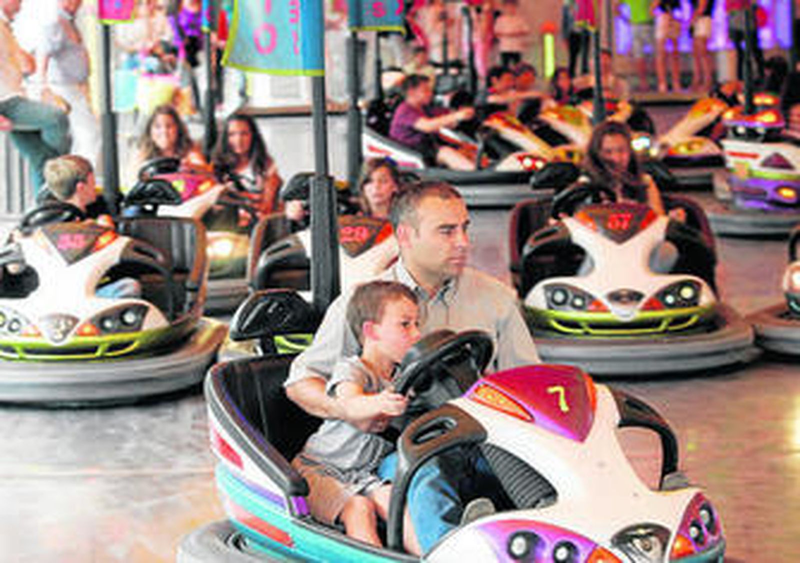 Un padre, junto a su hijo, en los coches de choque.