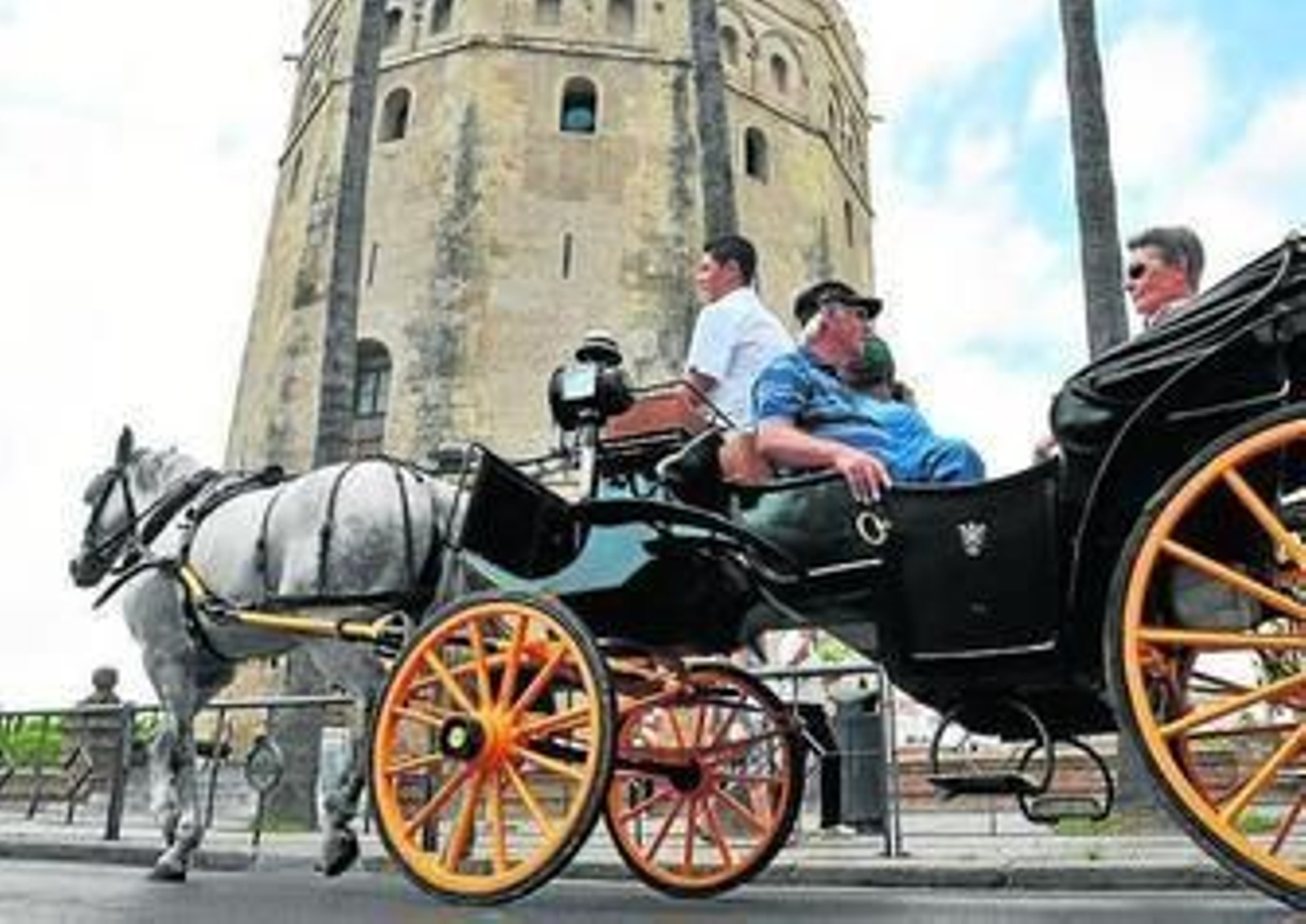 Turistas en un coche de caballos por el Paseo de Colón.