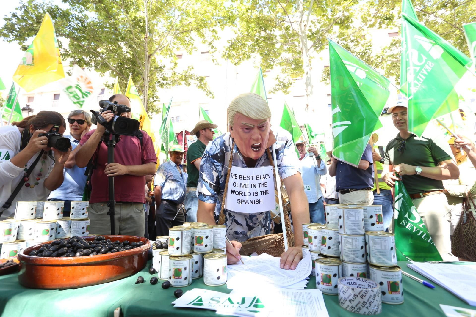 Un falso Donald Trump firma un manifiesto en defensa de la aceituna negra durante una protesta en Sevilla. Un falso Donald Trump firma un manifiesto en defensa de la aceituna negra durante una protesta en Sevilla.