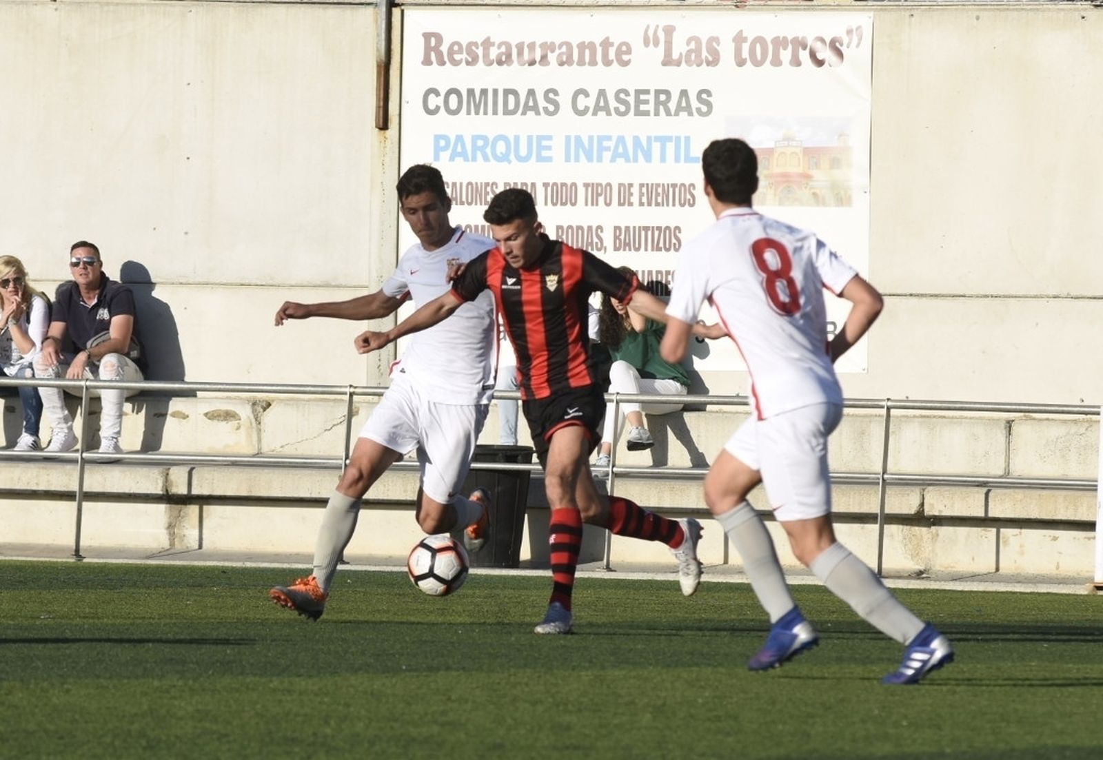 Un jugador del Séneca trata de sacar el balón jugado entre dos rivales del Sevilla.