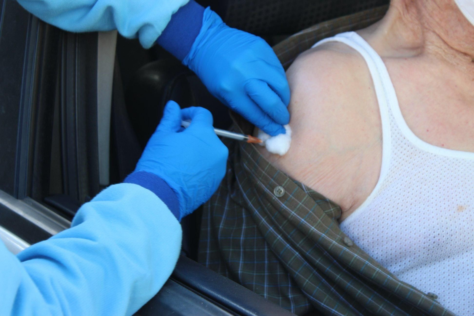 Una persona mayor recibe una dosis de la vacuna desde el coche.