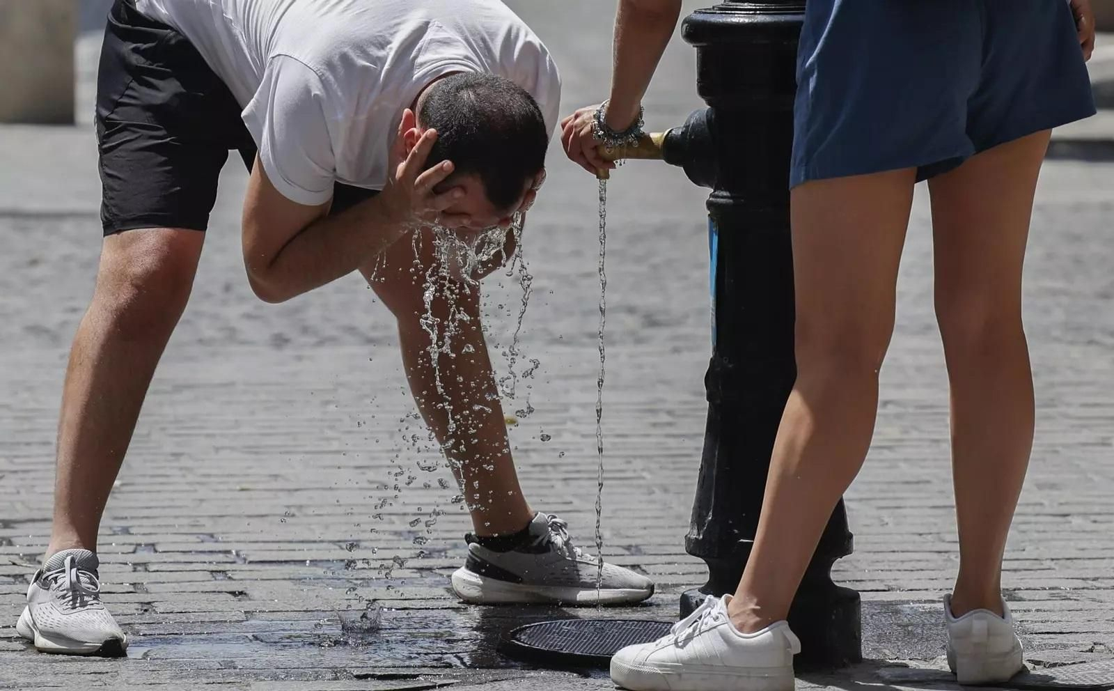 Gente refrescándose en una fuente en Sevilla.