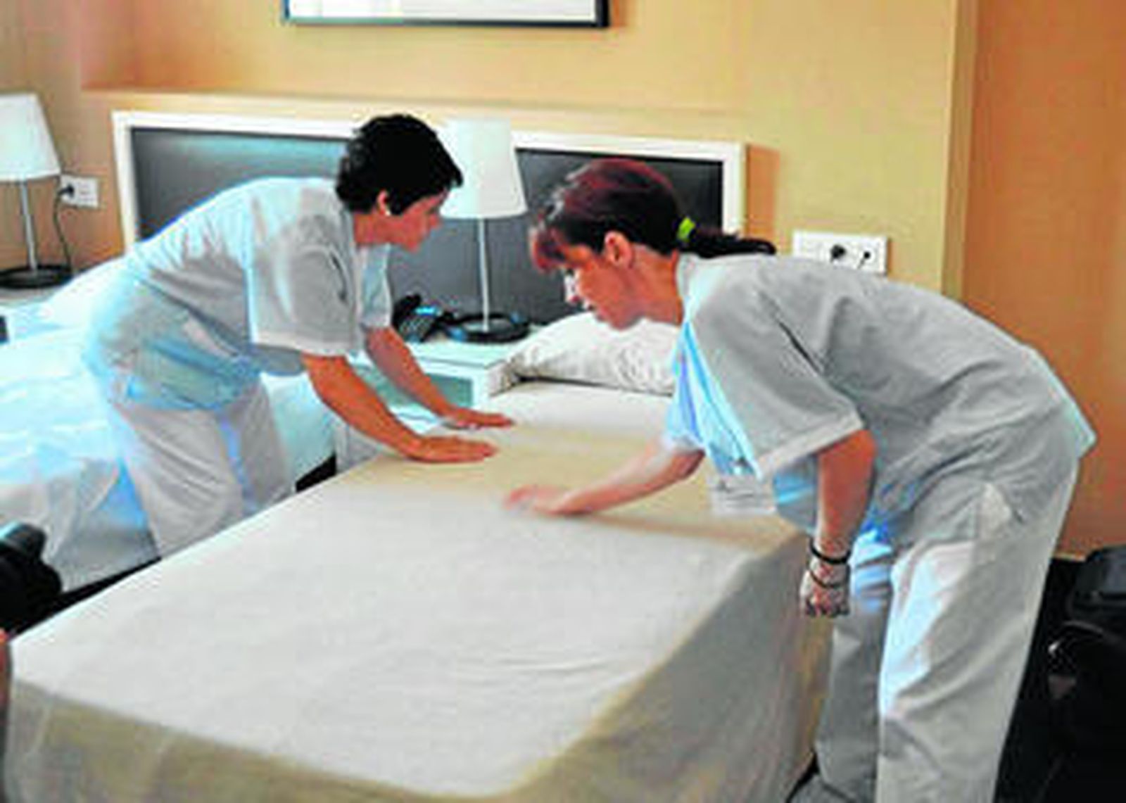 Dos camareras de piso ponen a punto la habitación de un hotel.