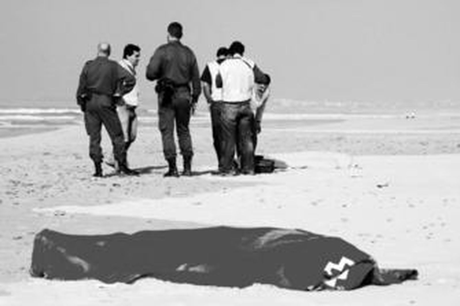 En primer término, uno de los cadáveres de los inmigrantes fallecidos ante la presencia de varios agentes de la Guardia Civil, ayer en Conil.