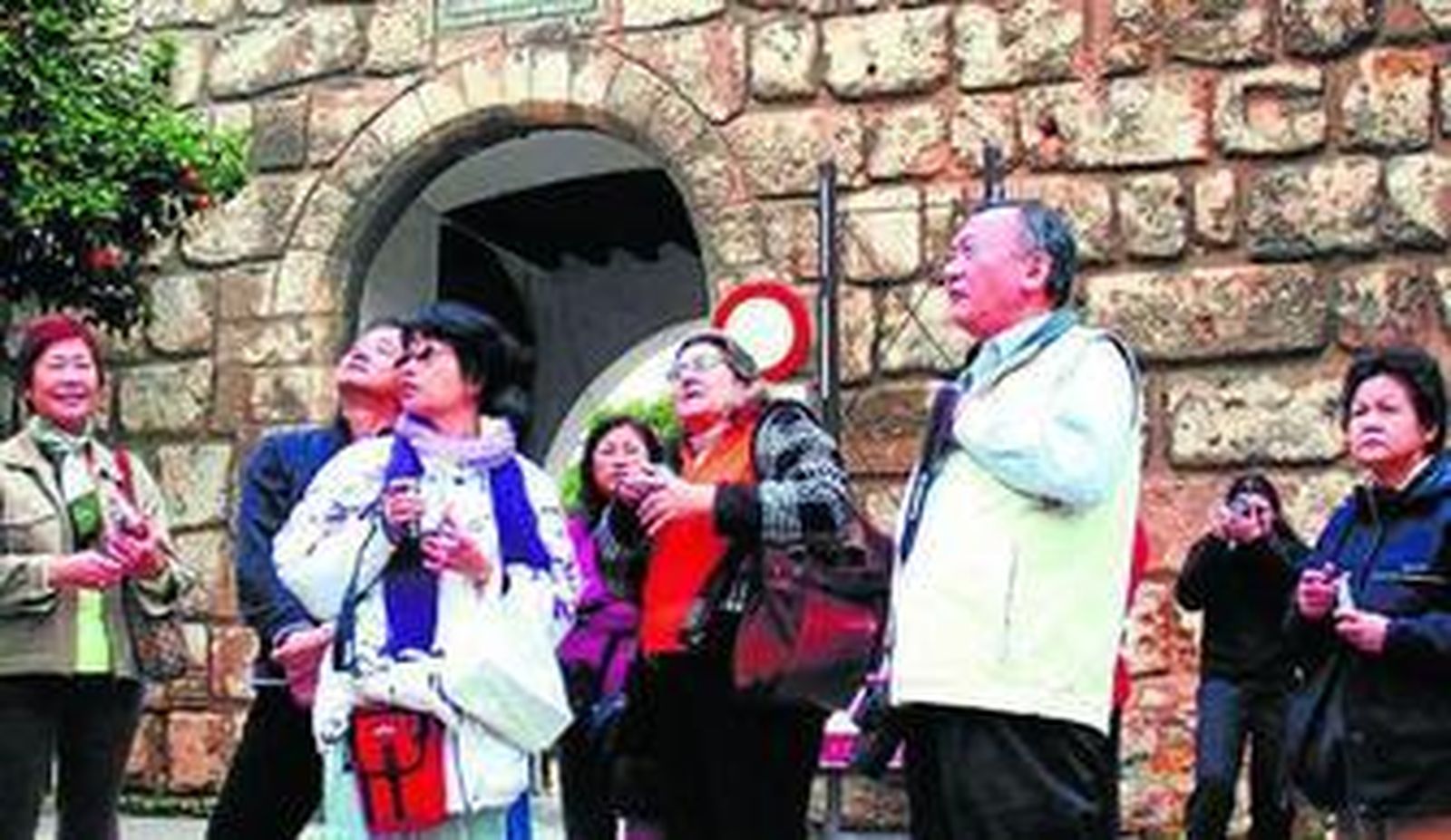Una guía ofrece sus explicaciones a un grupo de japoneses en la entrada del Alcázar de Sevilla.