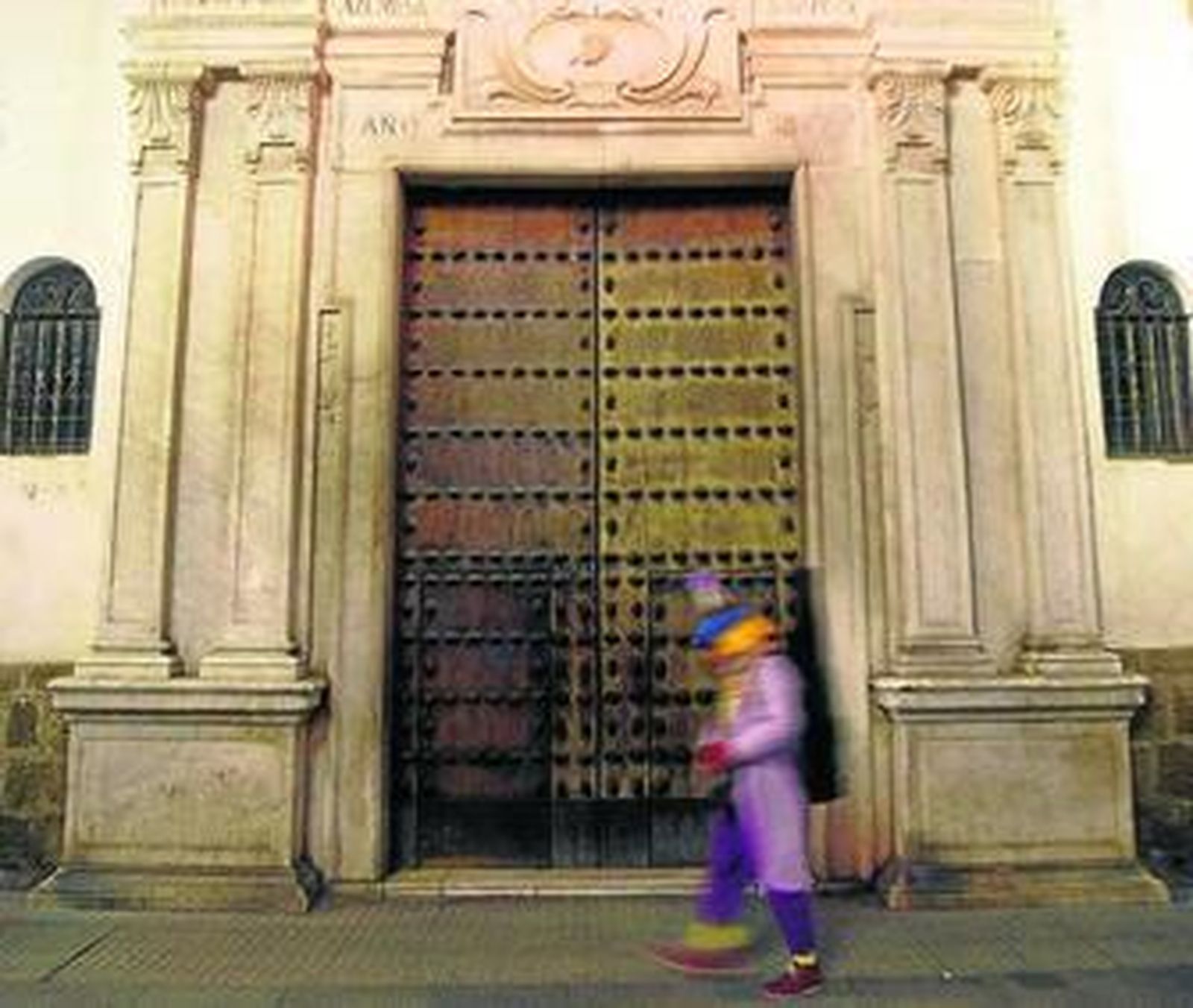 Una persona disfrazada pasa ayer tarde por la puerta de San Agustín, cerrada.