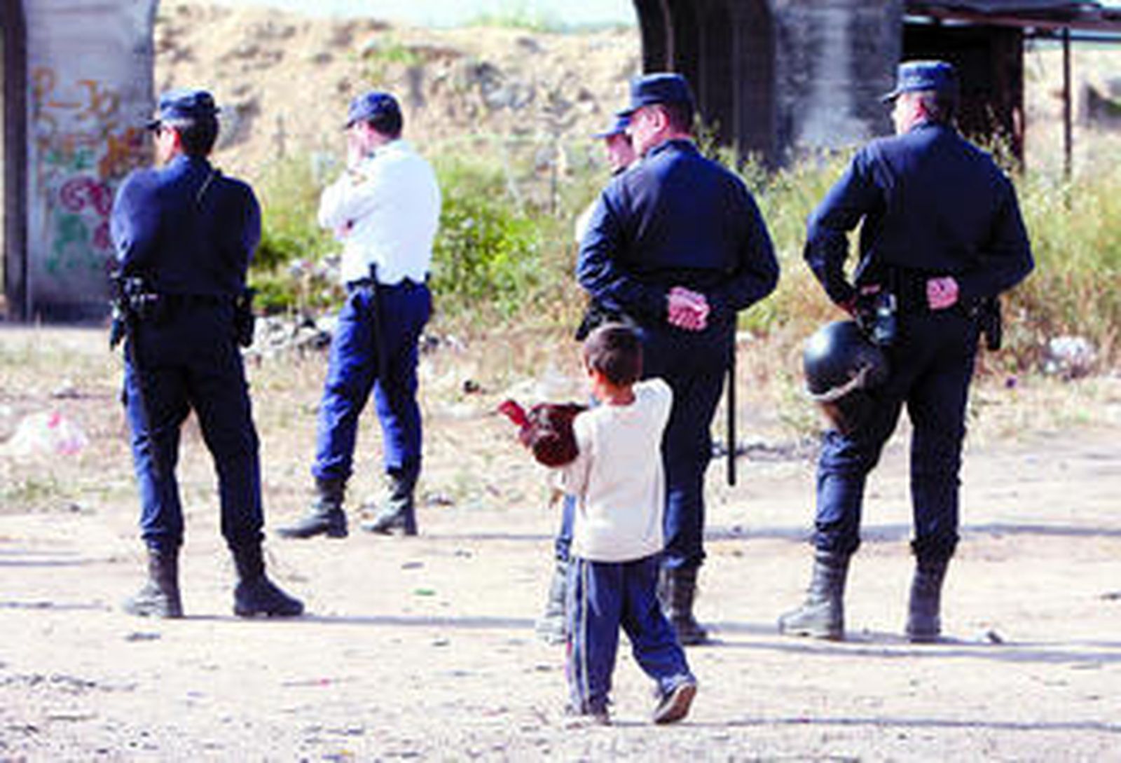 Un niño carga con un pavo ante la presencia de varios agentes de la Policía Nacional, ayer en el poblado junto al puente de hierro.
