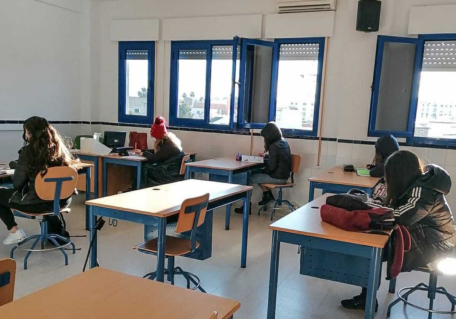 Alumnos abrigados con chaquetones y gorros en el interior de un aula en un instituto de Chiclana.