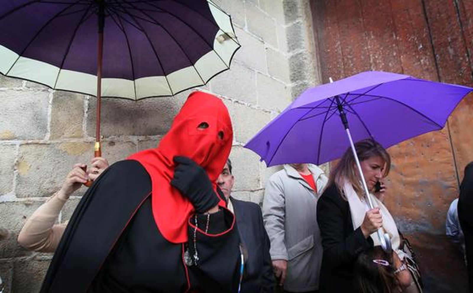 Un nazareno de Los Judíos pasa bajo un paraguas en las inmediaciones de la iglesia de San Mateo.

Foto: Miguel Ángel González