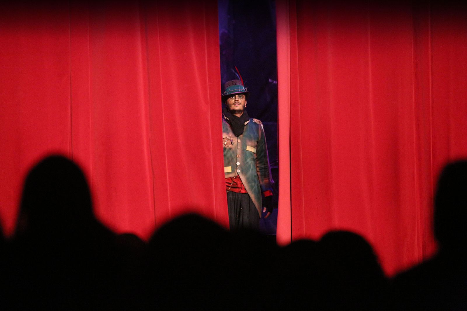 Uno de los participantes se asoma al escenario aún con el telón por descorrer.