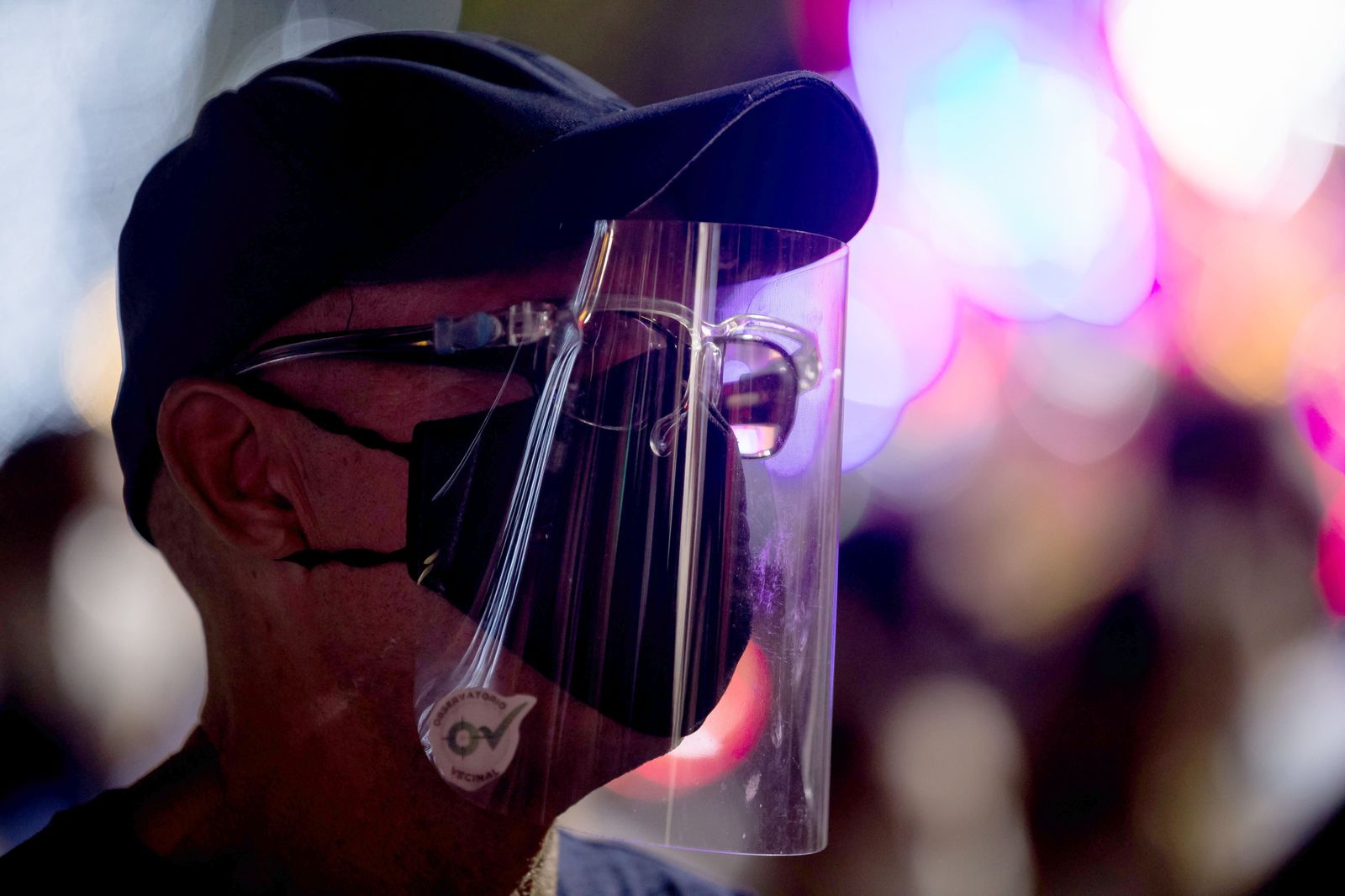 Un hombre con mascarilla, gafas de protección y protector facial