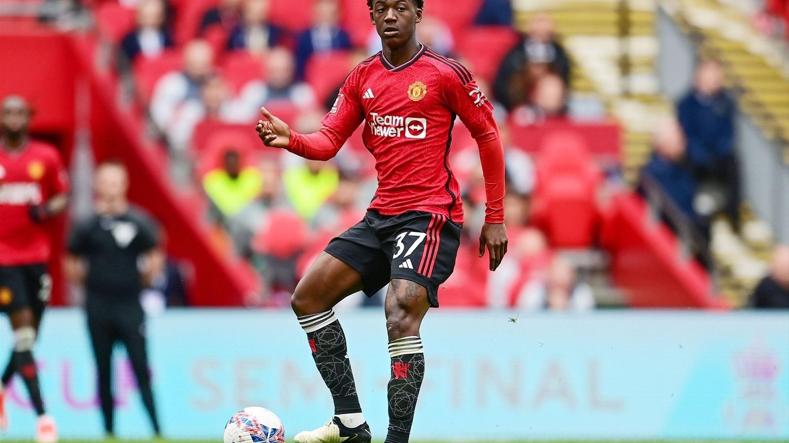 Kobbie Mainoo  golpea el balón en un partido con el Manchester United.