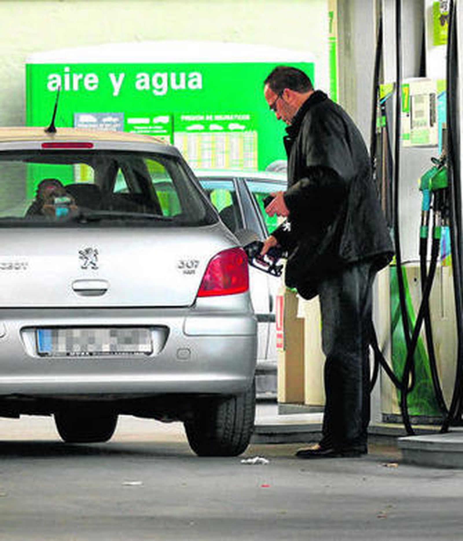 Un señor reposta gasolina en una estación de servicio.