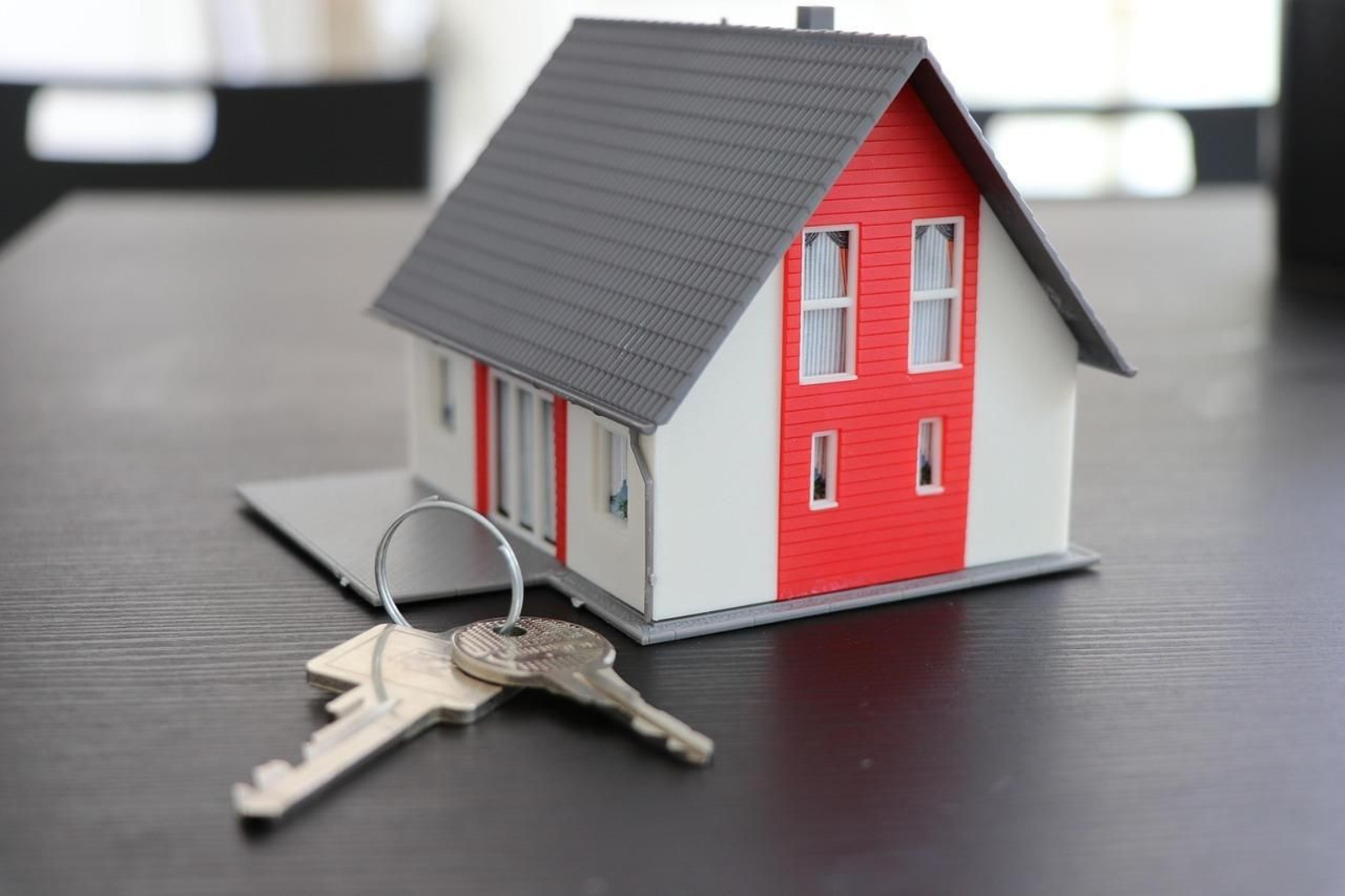 Llaves de una vivienda junto a una maqueta de una casa.