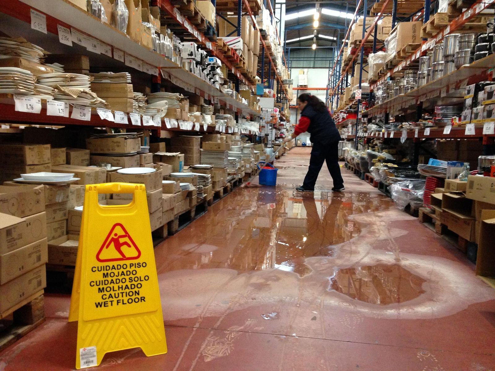 Una empleada de Comercial Patricia intenta secar el agua de una de las calles del establecimiento.