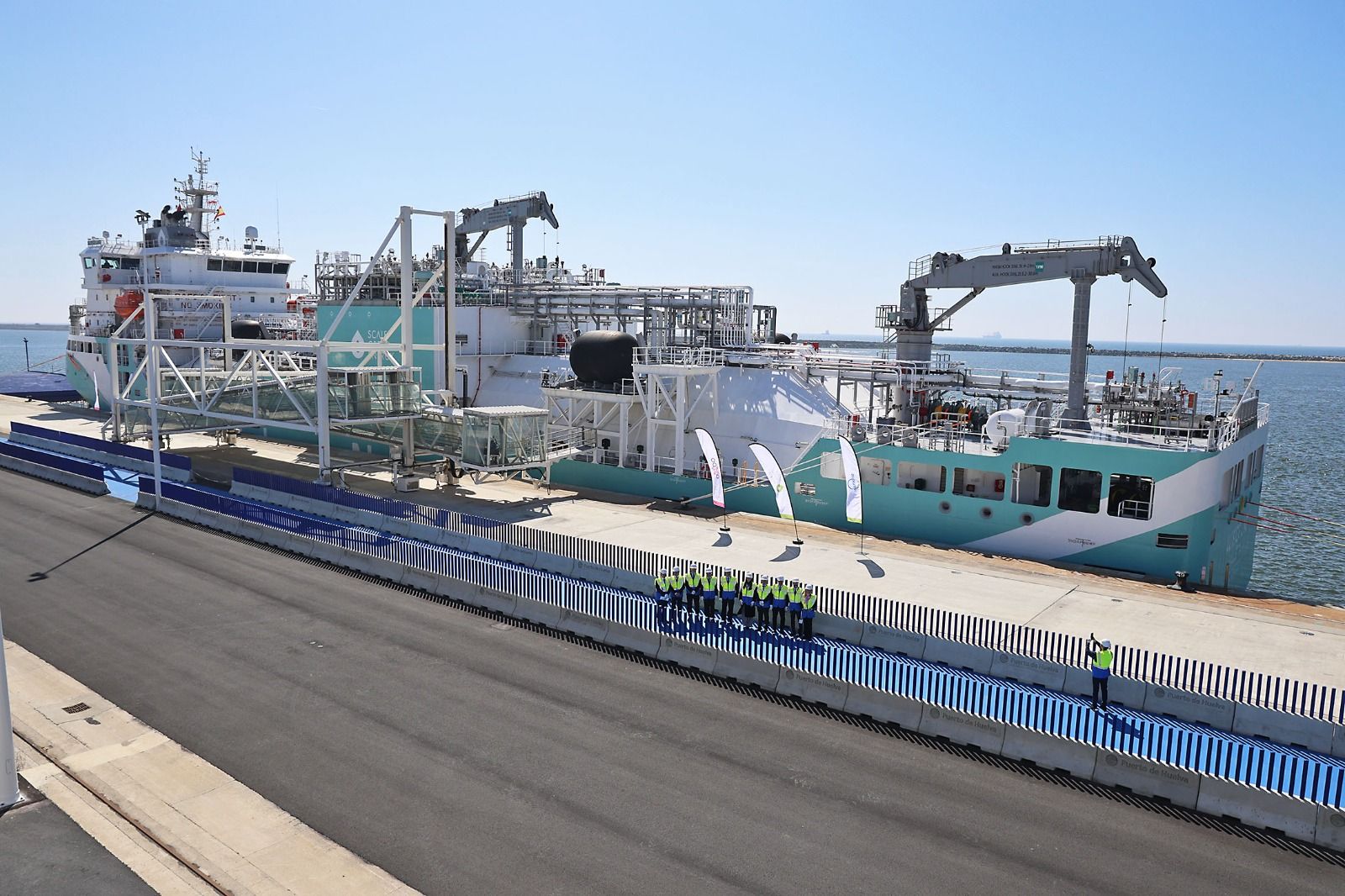 Autoridades y representantes empresariales posan delante del ‘Alisios LNG’, atracado en el Muelle Sur del Puerto de Huelva.