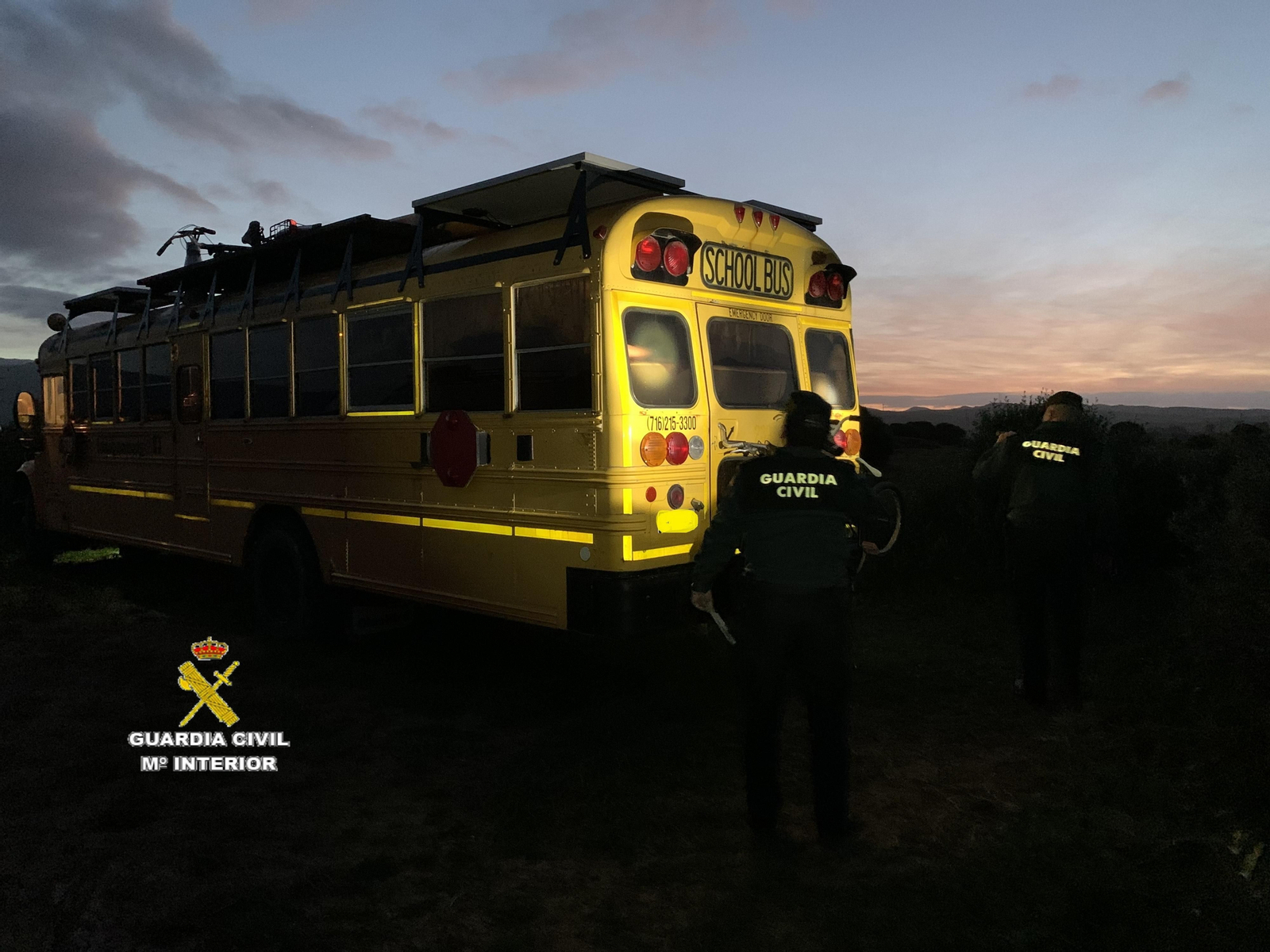 Dos agentes de la Guardia Civil inspeccionan un antiguo autobús escolar, habilitado como caravana, en Tarifa.