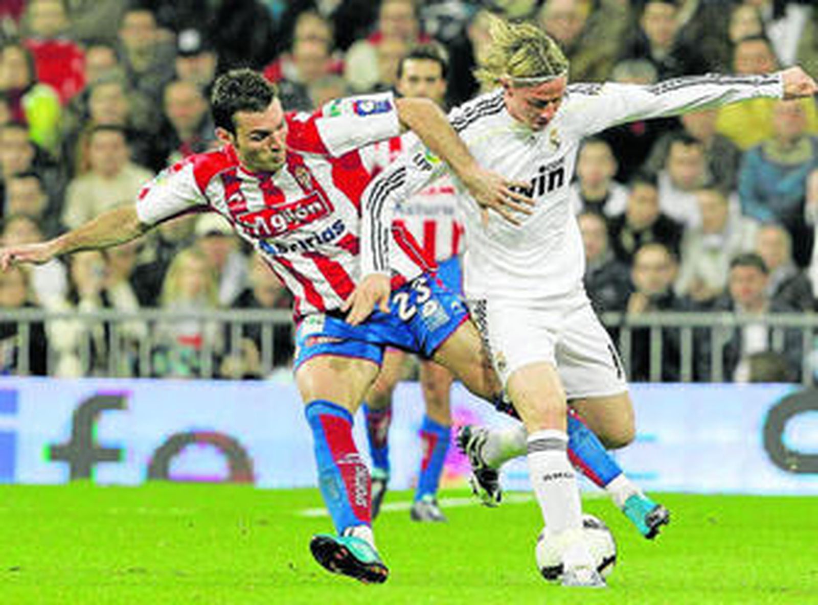 Guti protege el balón ante la presión del sportinguista Barral.