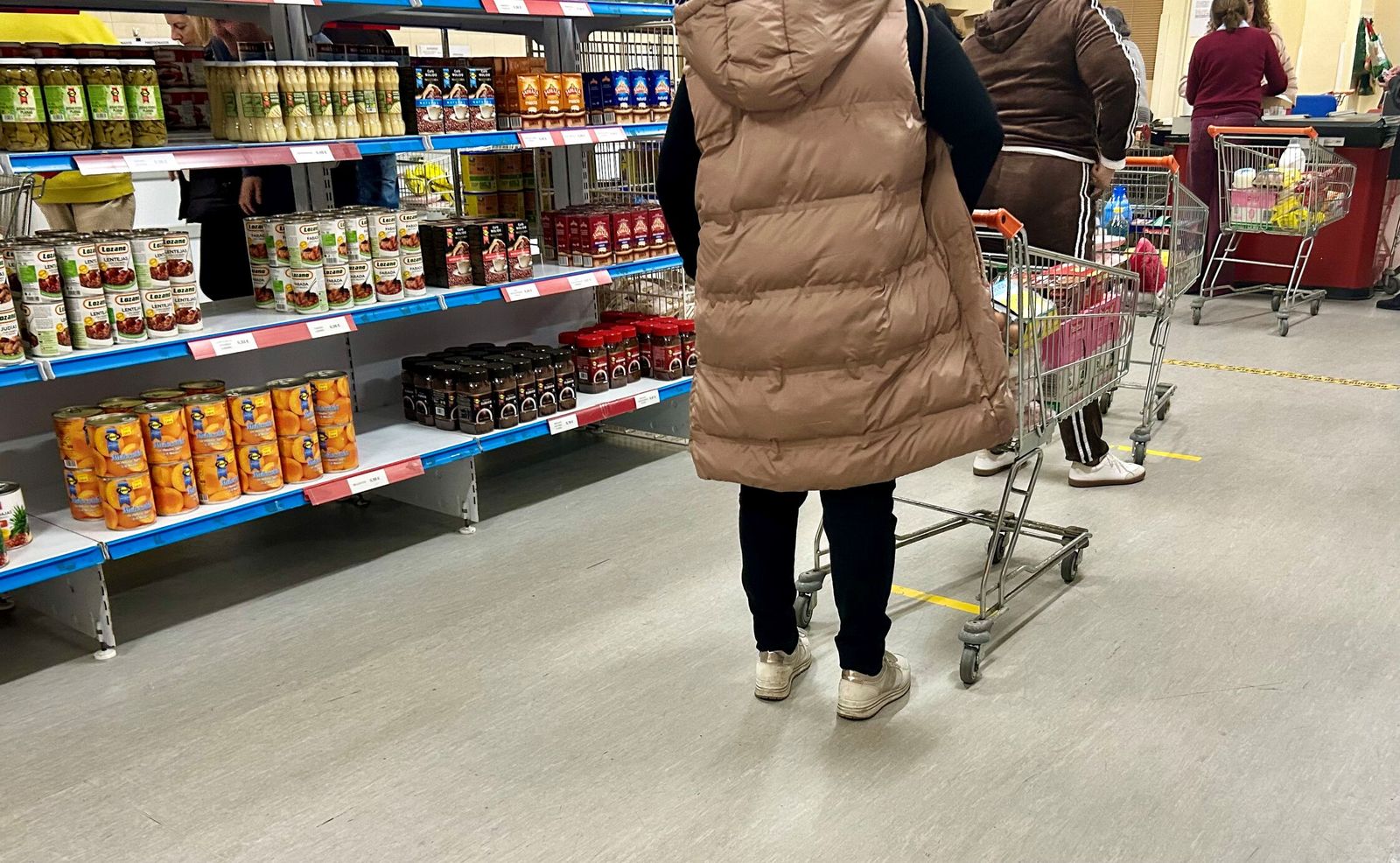 Varias mujeres esperan en la cola de la caja de un economato de Sevilla.