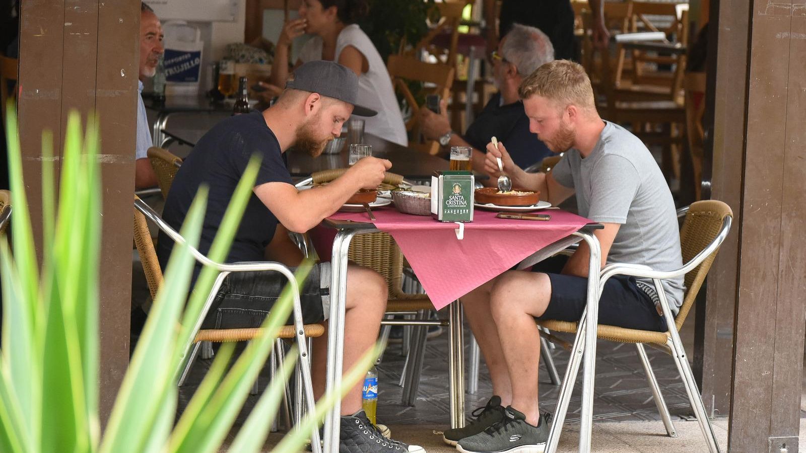 Dos turistas comen en la terraza de un restaurante en Tarifa Dos turistas comen en la terraza de un restaurante en Tarifa