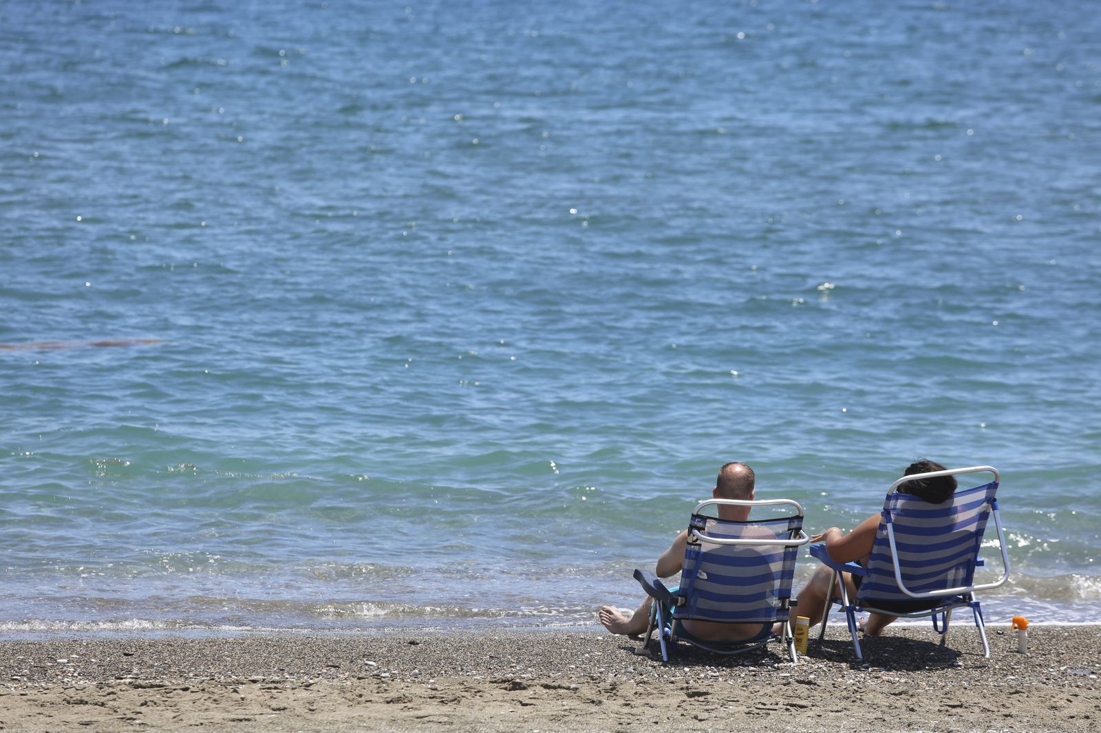 Dos personas, sentadas frente a la orilla del mar en Málaga.