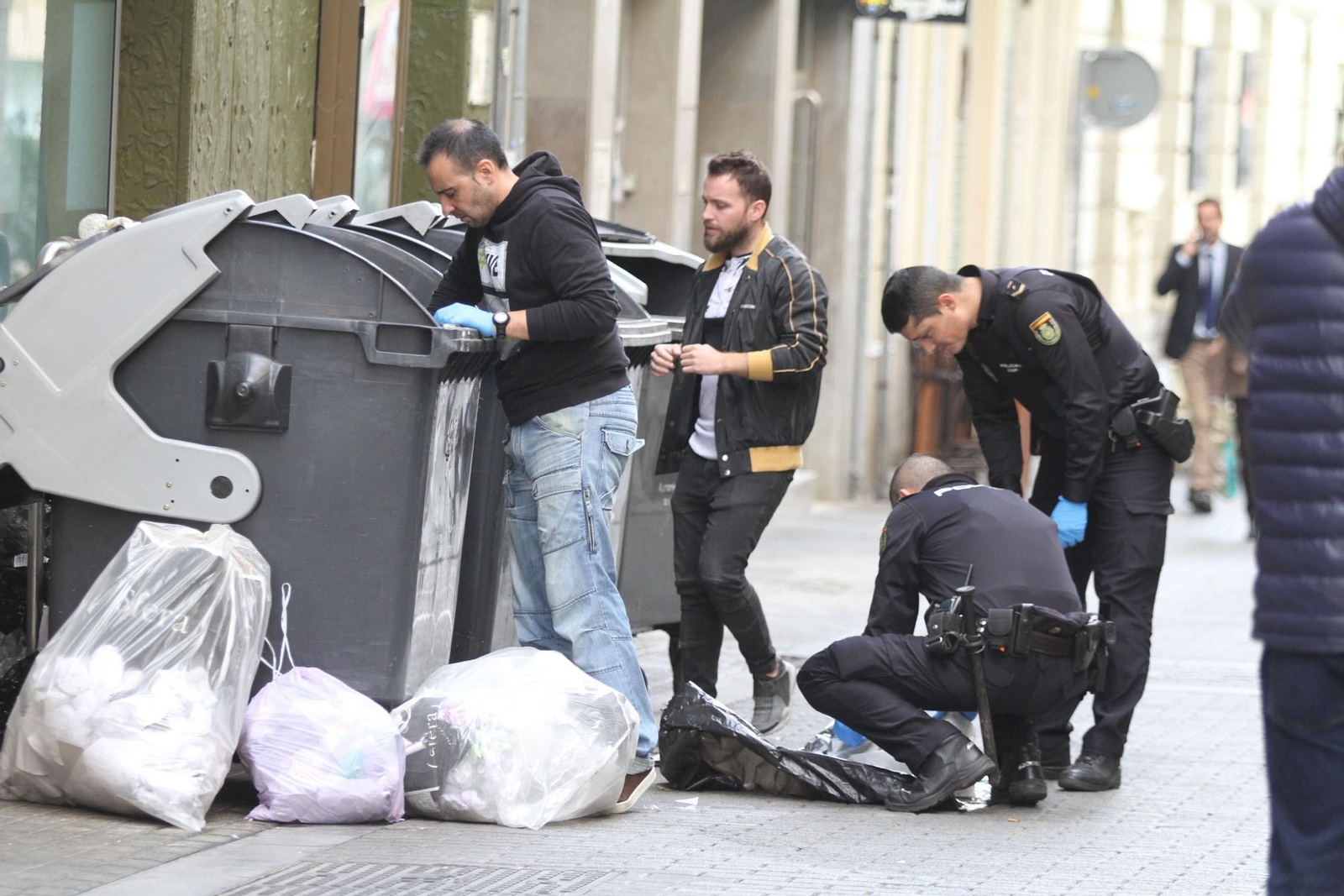 Agentes de la Policía Nacional rebuscan en los contenedores hasta dar con el embrión dentro de una bolsa este jueves.