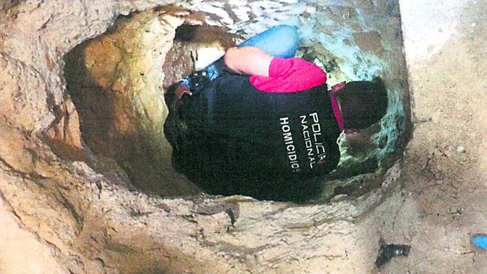 Un agente dentro de la fosa séptica donde sepultaron los cadáveres.