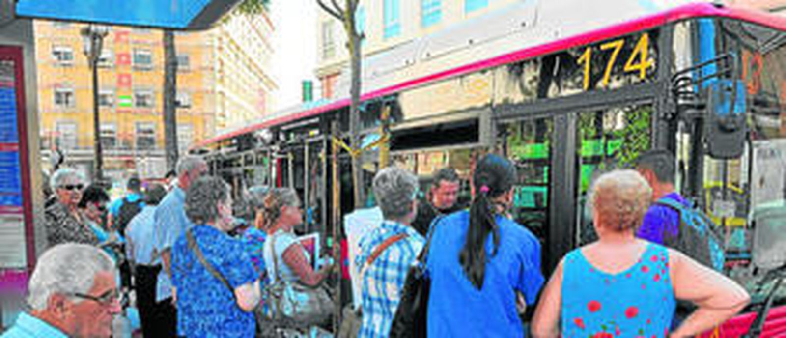 Un grupo de usuarios esperan en una parada situada en la Plaza del Duque para subir al autobús.