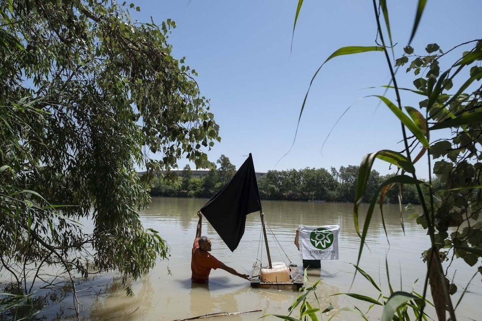 Un activista coloca una bandera negra en un punto del Guadalquivir afectado por la mina.