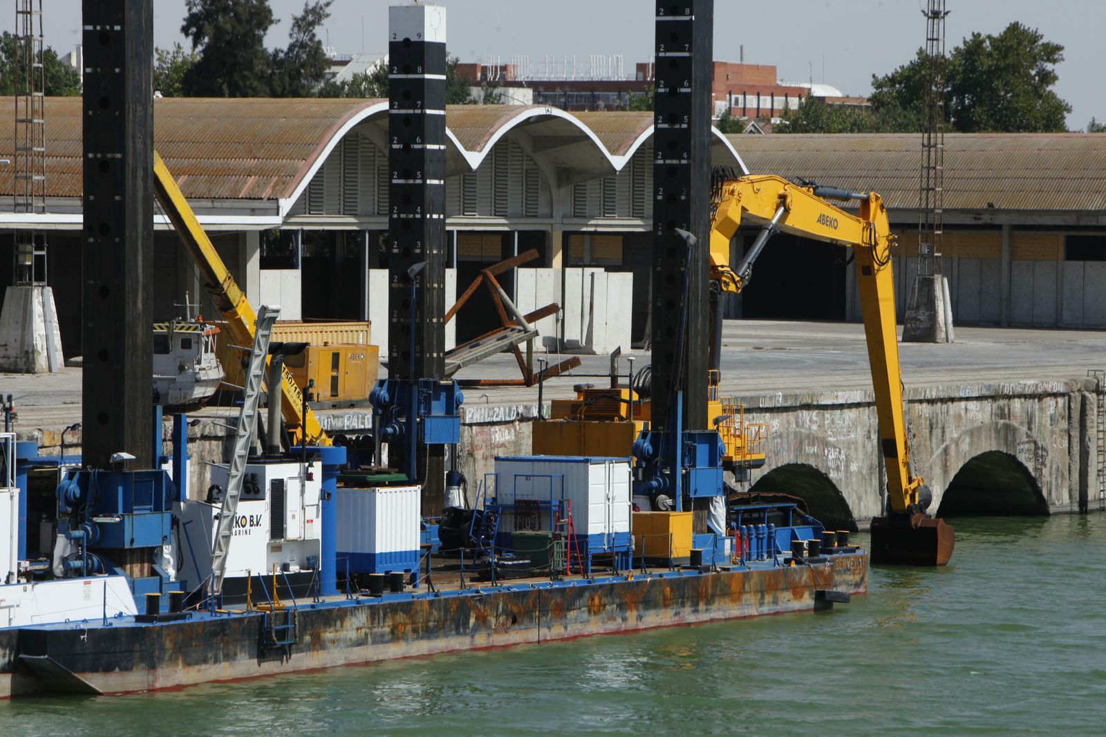 La draga retroexcavadora que interviene está atracada en el Muelle de Tablada.